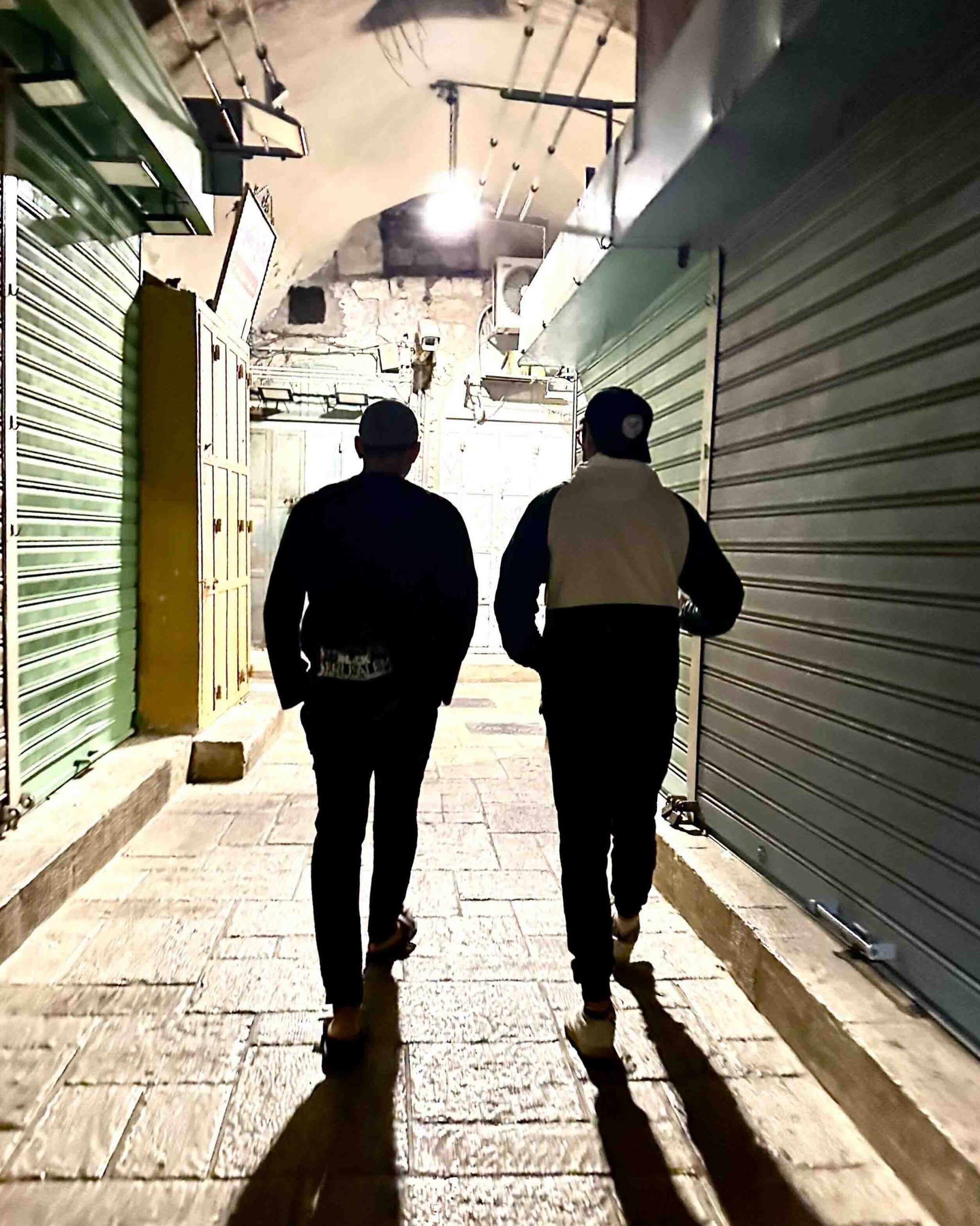 A photo of Kashif Shaikh and Rami Nashashibi walking through an alleyway in Palestine