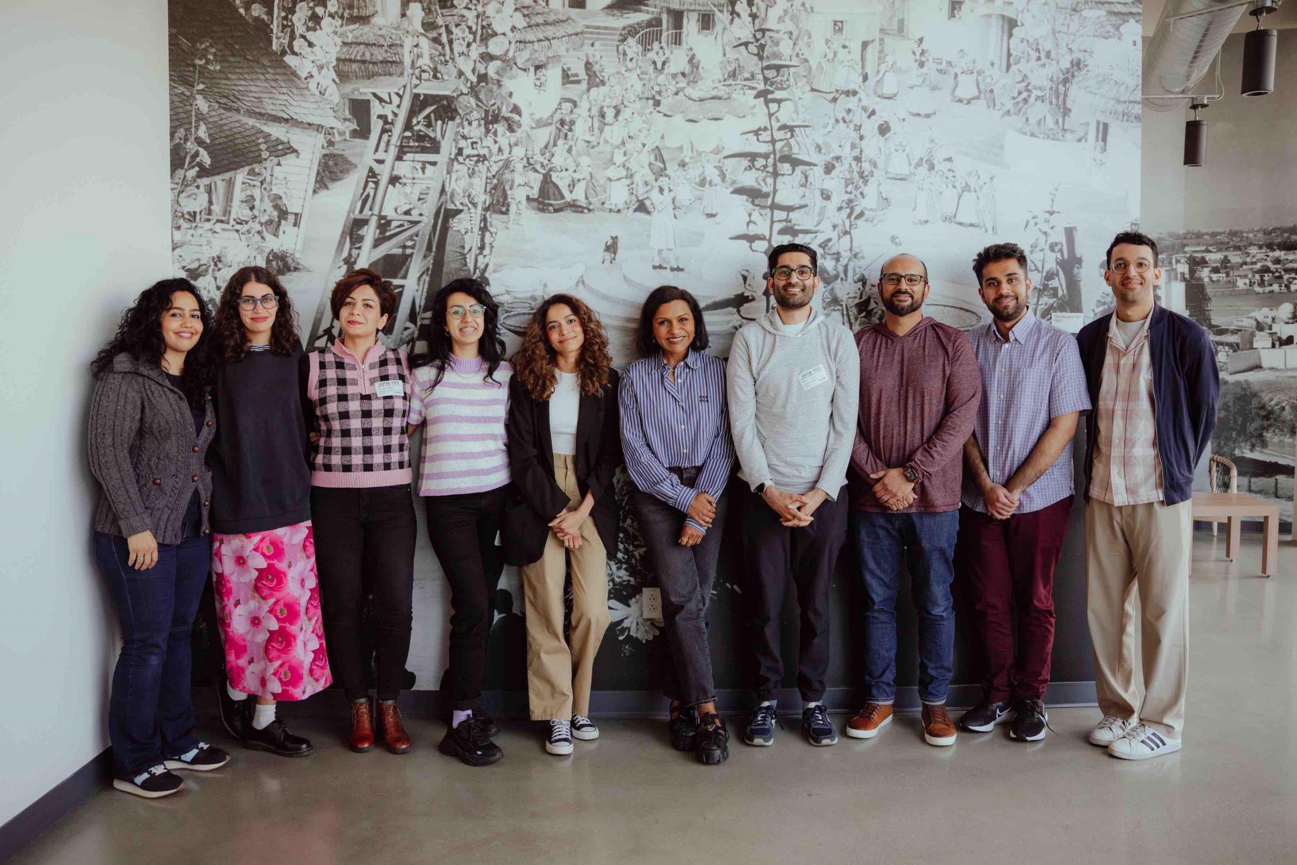 All 10 of the Pillars Artist Fellows pose and smile in a line with Mindy Kaling in the center