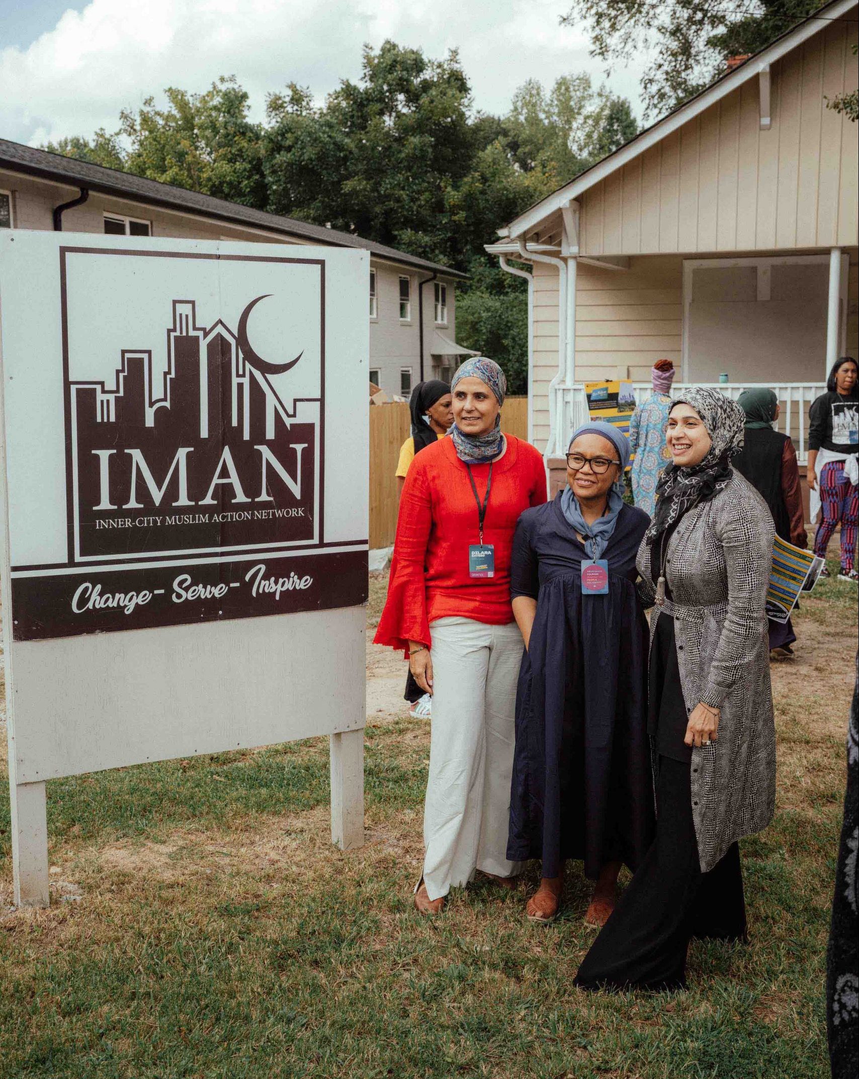 Pillars community members posing in front of an IMAN sign that reads 