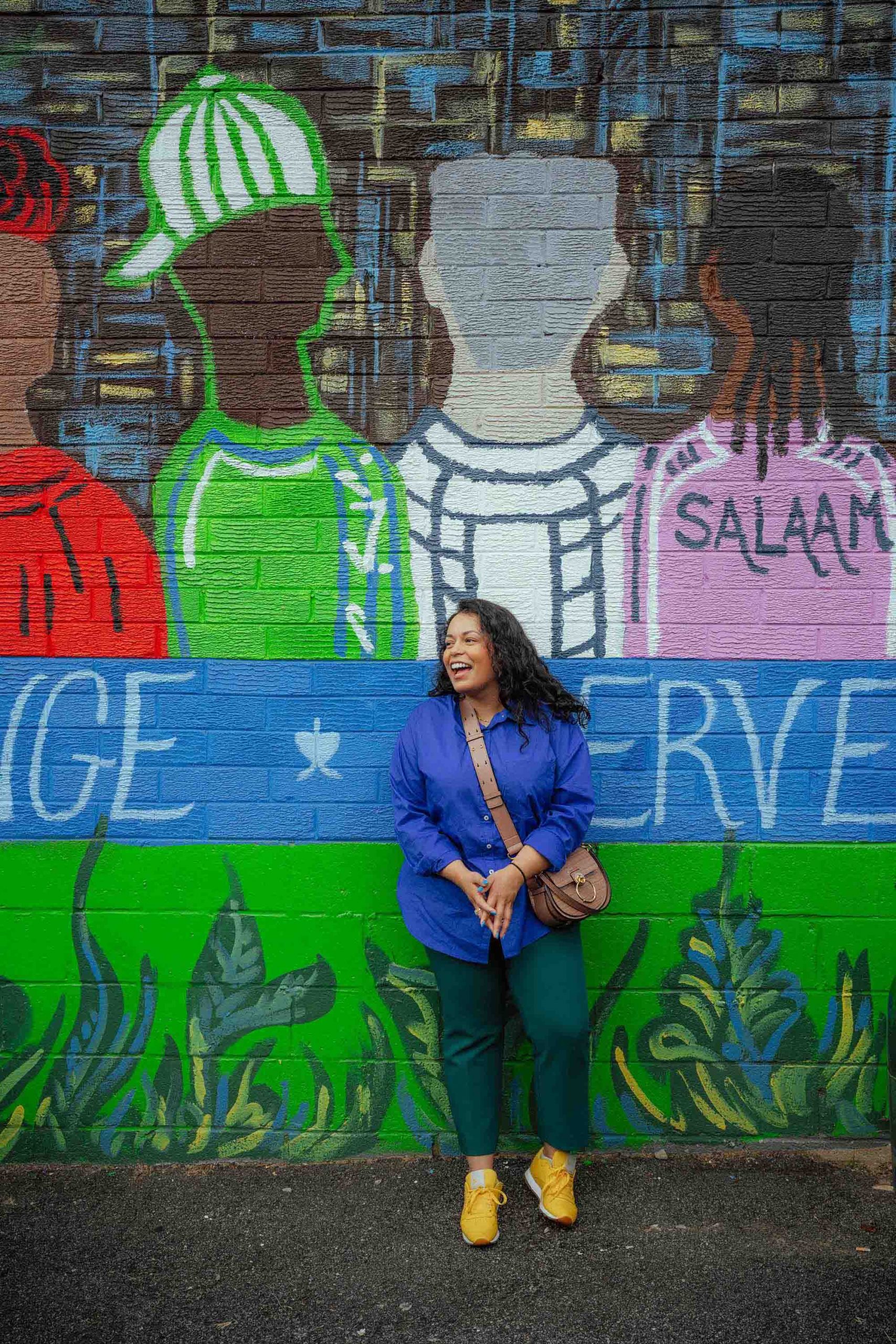 Emgage's Aysha Ahmed poses in front of a colorful mural