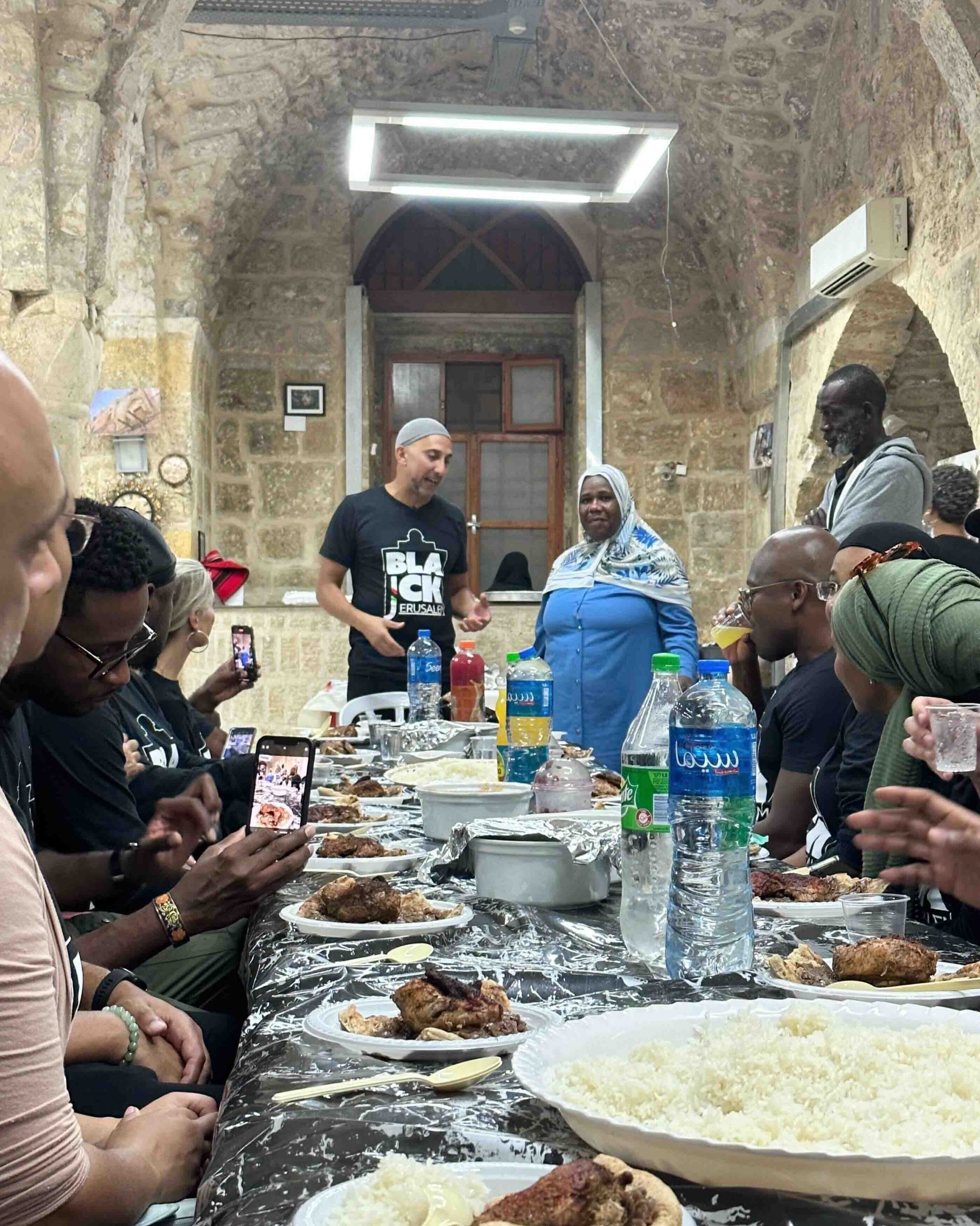 A photo of Rami Nashashibi engaging in a conversation, speaking to an attentive group during a dinner event